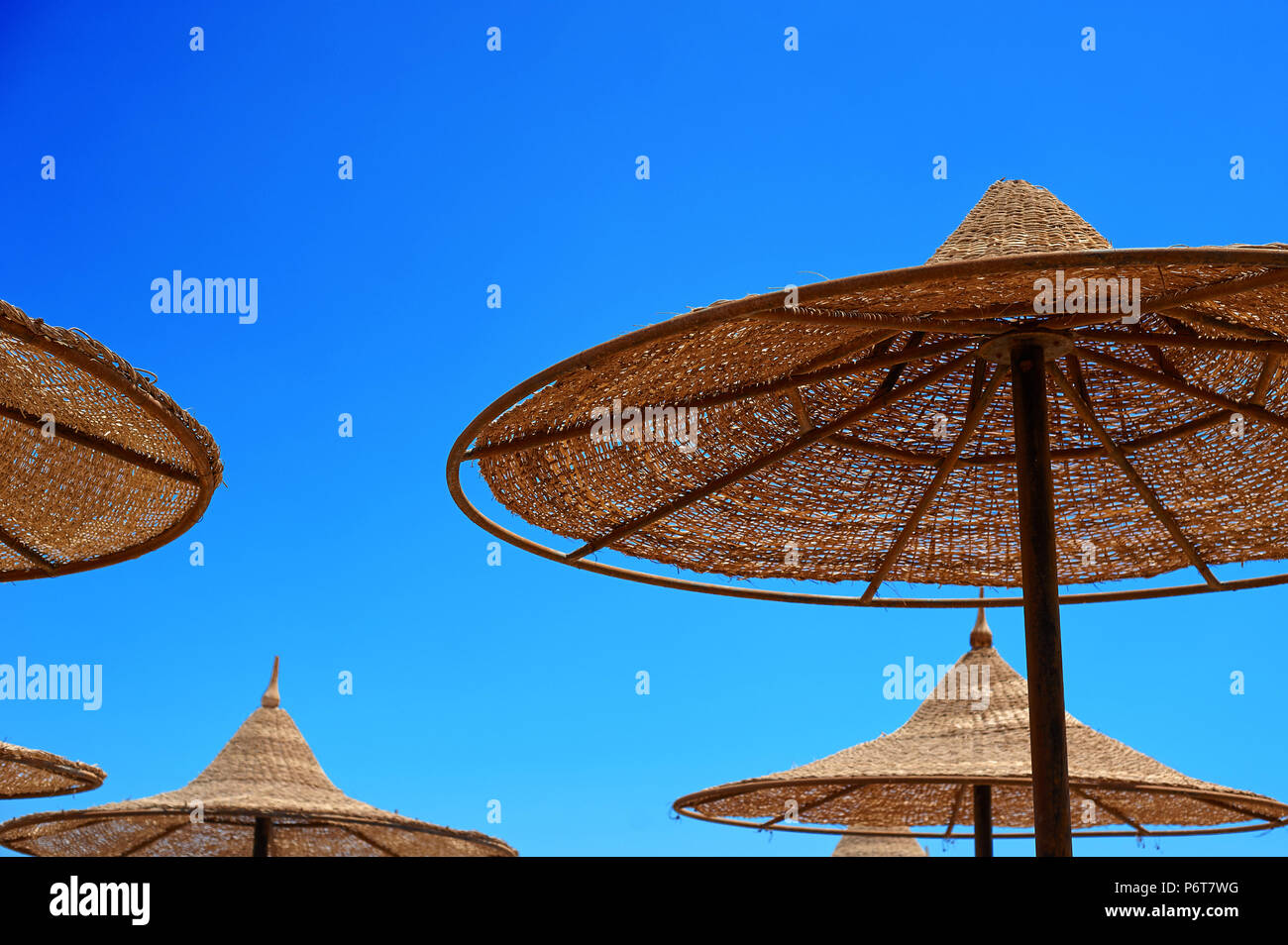 Sonne - Schutz wicker Sonnenschirme am Strand gegen den Himmel, das Konzept der Sommer Tourismus Stockfoto