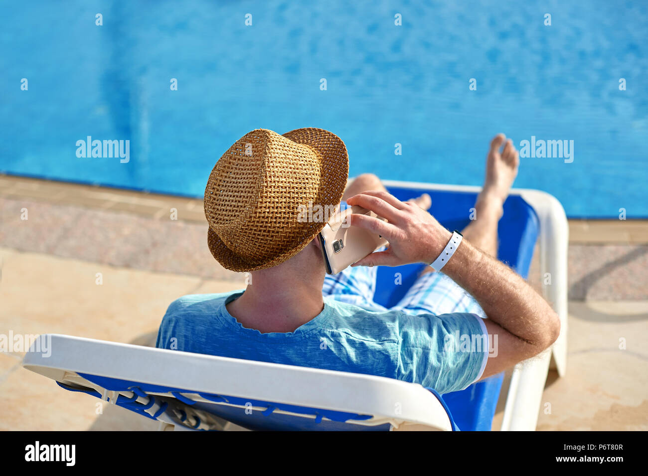 Mann mit Handy im Urlaub am Pool im Hotel, Konzept der Freiberufler arbeiten für sich selbst im Urlaub und Reisen Stockfoto Mann mit Handy im Urlaub am Pool im Hotel, Konzept der Freiberufler arbeiten für sich selbst im Urlaub und Reisen Stockfoto