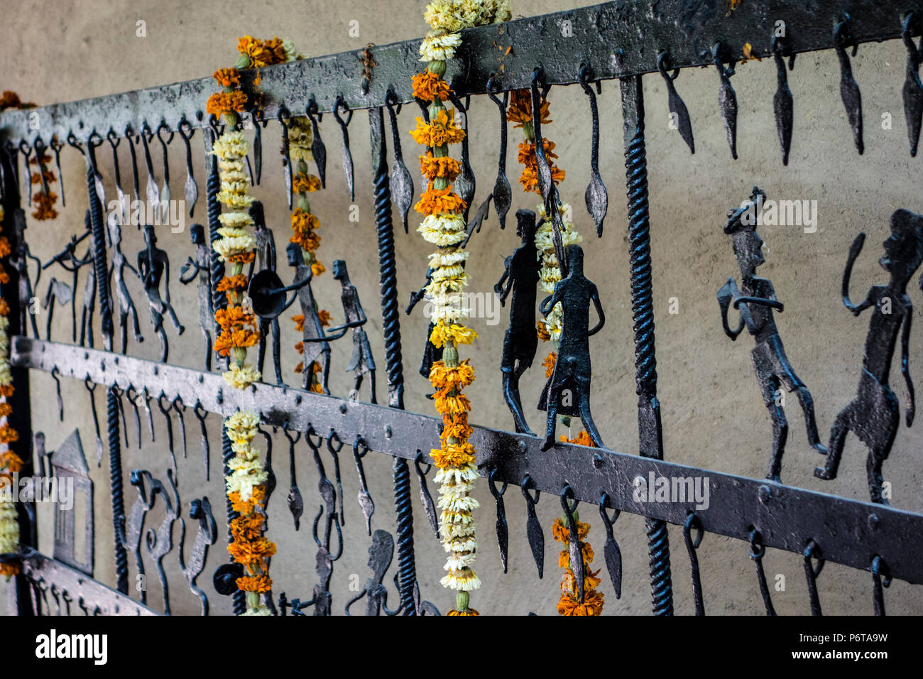 Ausstellung von einem schmiedeeisernen Tor oder Zaun von Bastar, Chhattisgarh hing mit Blumengirlanden in der Nationalen Crafts Museum, New Delhi, Indien Stockfoto