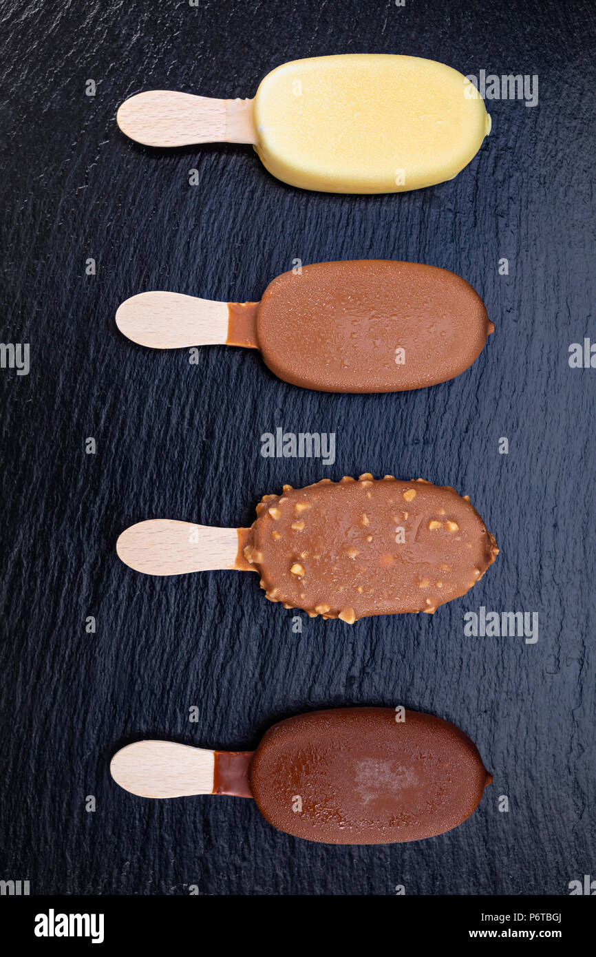 Eis auf Stick mit Schokolade auf schwarzen Stein Schiefer board abgedeckt. Stockfoto