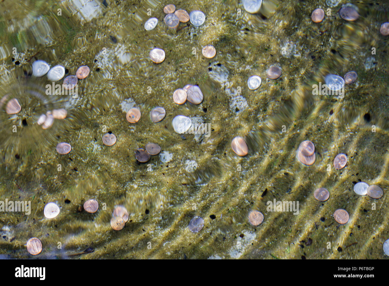 Machen Sie einen Wunsch. Wellen von Wasser Wellen über Münzen, die in einem Brunnen. Stockfoto