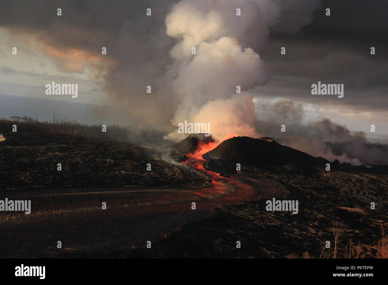 Lava weiter Magma aus dem 180 Fuß hoch spritzt Kegel mit Lave in einen offenen Kanal in Spalte 8, die der Ausbruch des Kilauea Vulkans Juni 30, 2018 in Hawaii verursacht fließt zu spucken. Die letzte Eruption weiter zerstören Häuser, zwangen Evakuierungen und spucken Lava und Giftgas auf der grossen Insel von Hawaii. Stockfoto