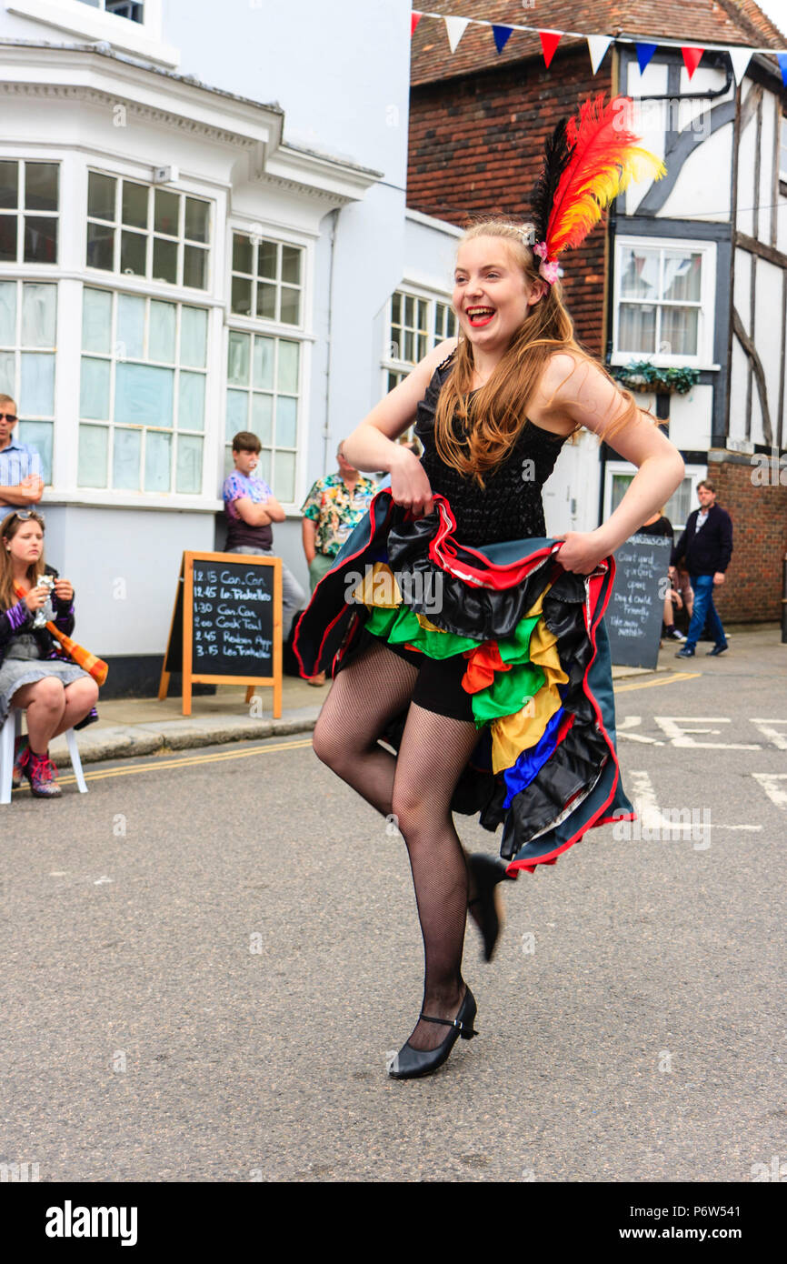 Junge Frau, junges Mädchen, Durchführung der Can-Can in einer Straße in eine festliche Veranstaltung. Bühne mit Musikern hinter Ihnen. Holding Rock bis zur Taille. Stockfoto