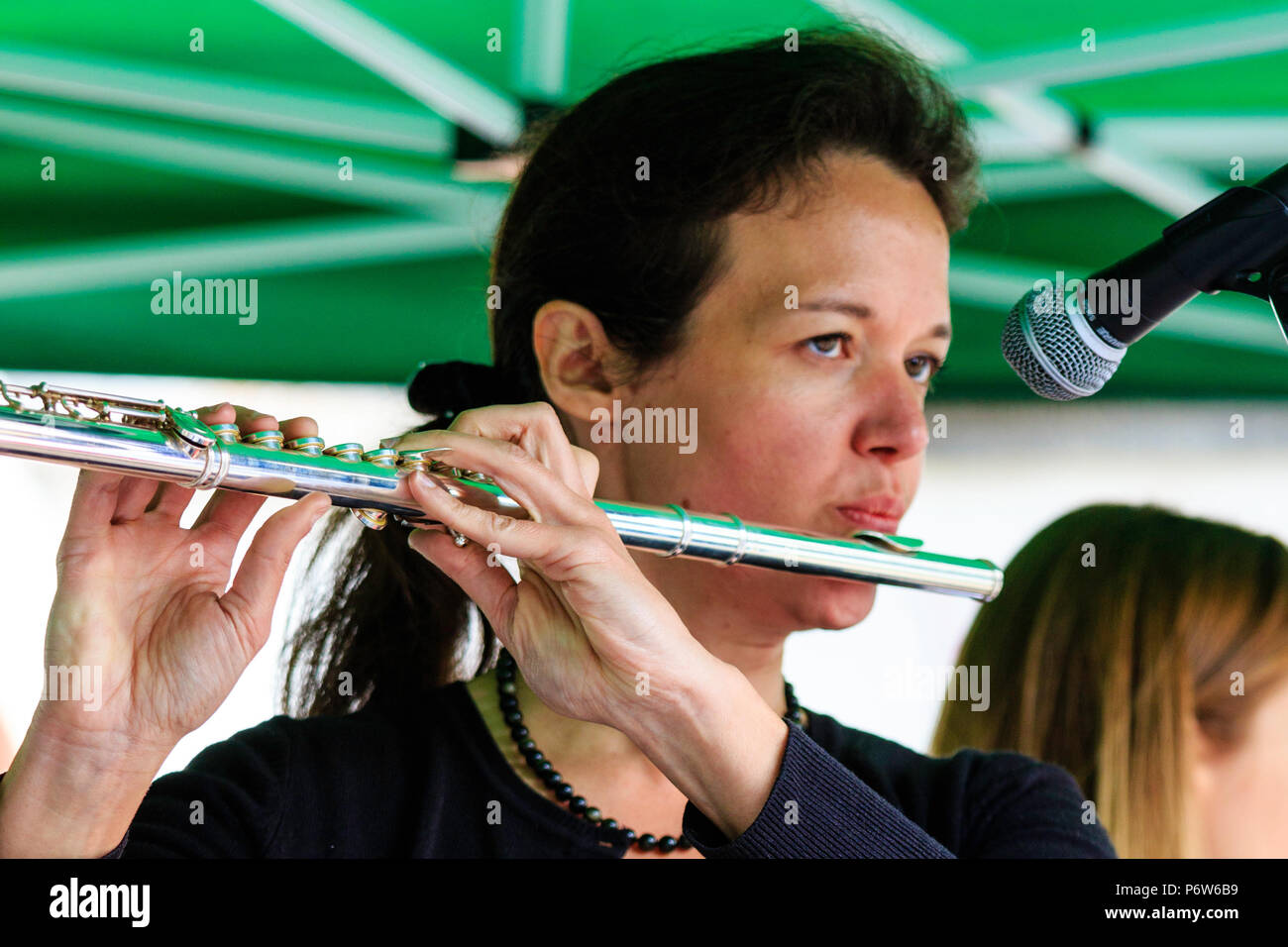 Kaukasische Frau spielen Flöte in Open Air Konzert. Karine Magnier stehend mit der französischen Band folk rock Triskelles. Nahaufnahme des Gesichts. Stockfoto