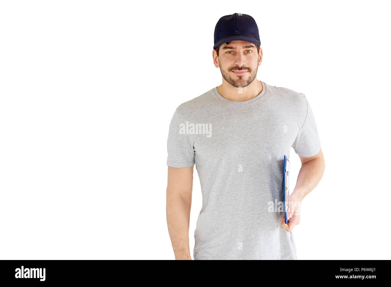 Portrait von gutaussehenden jungen Mann an vereinzelten weißen Hintergrund. Ein Lächeln auf den Lippen tragen Mann Baseballmütze und Holding Zwischenablage in seiner Hand. Stockfoto
