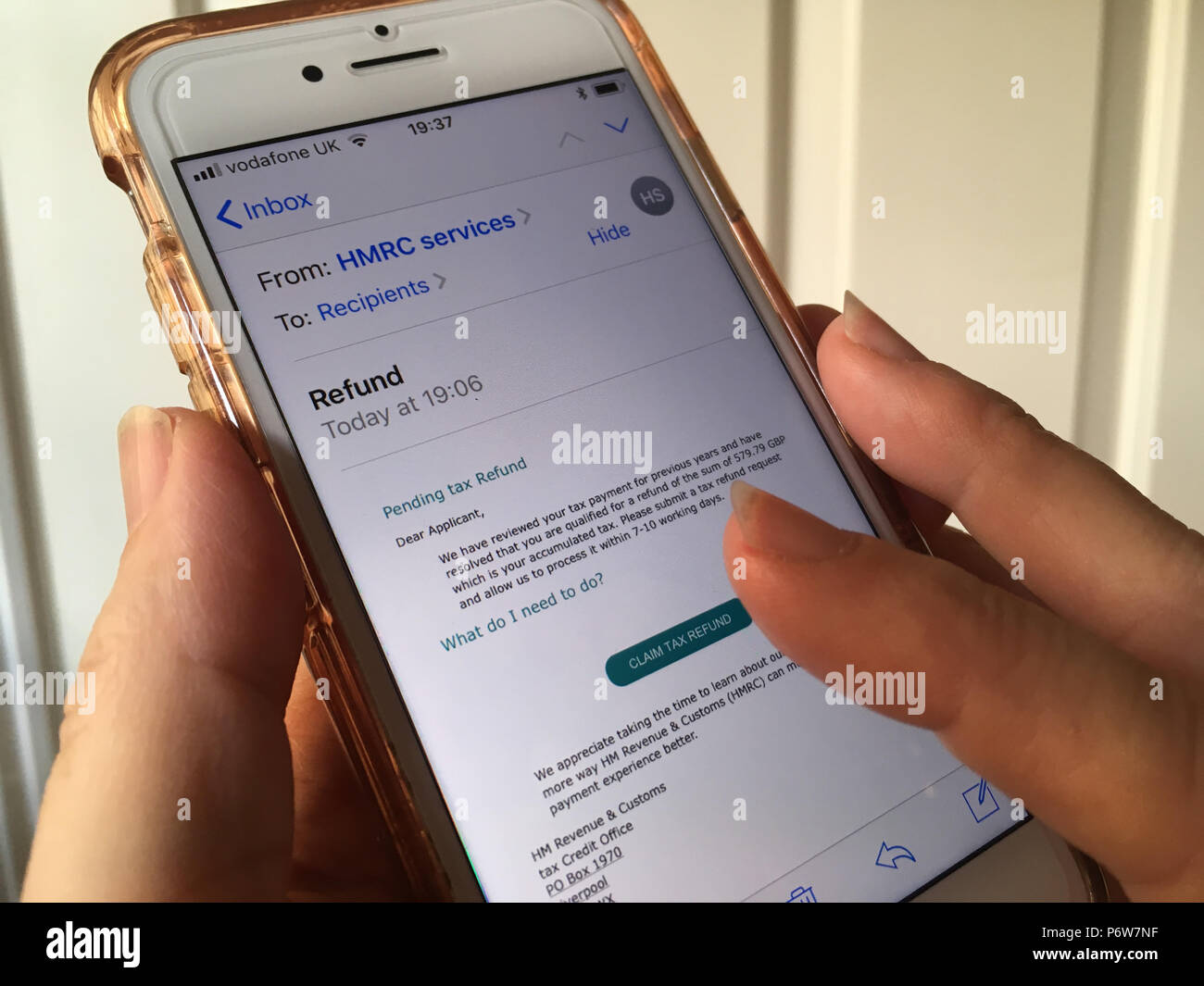 Handy in der Hand der Frau mit einem scam/Phishing-E-Mails, die angeblich von der HMRC, auf dem Bildschirm angezeigt werden Stockfoto