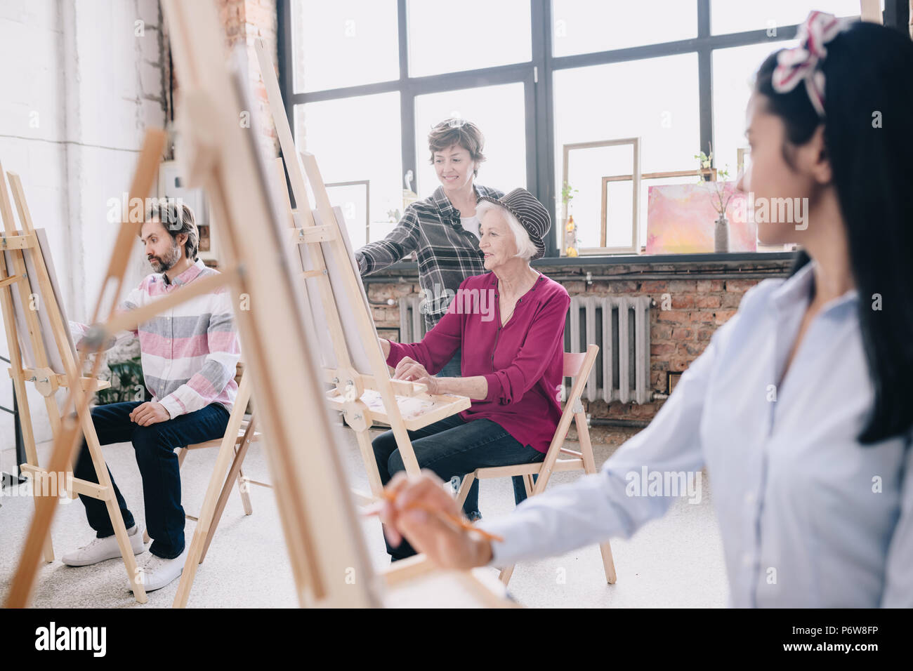 Portrait von eleganten Senior Frau Malerei an der Staffelei im Atelier ein Studium der Kunst mit lächelnd weibliche Lehrer, Kommentare, Szene, in einem geräumigen Sitzbereich s Stockfoto