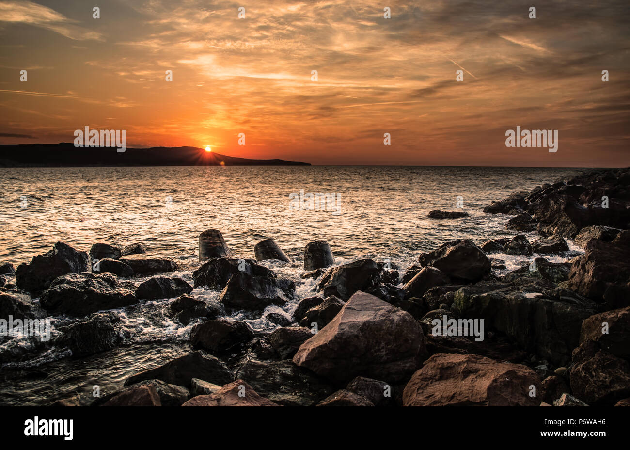 Dramatischer Sonnenuntergang am Meer mit Wellen Stockfoto