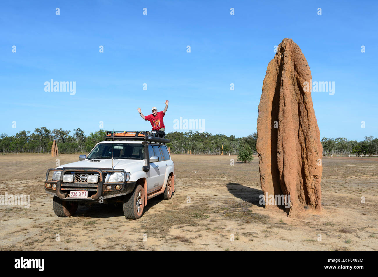 Touristische winken vom Dach seines 4X4 Nissan Patrol, stehen neben einem riesigen Termitenhügel Damm, Cape York Halbinsel, Far North Queensland, FNQ, QLD, Australien Stockfoto