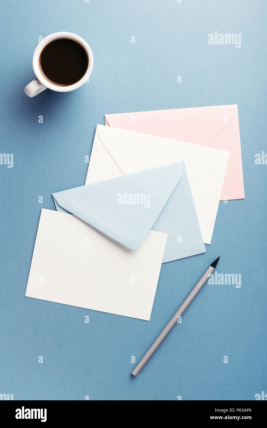 Gruppe von farbigen Umschläge und eine Tasse Kaffee auf blauen Tisch mit leeren. Korrespondenz Konzept. Mockup. Stockfoto