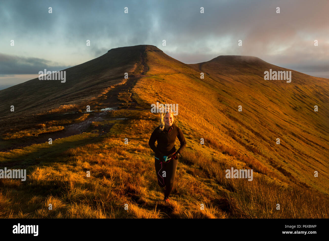 Läuferin mit den Gipfeln der Pen Y Fan (rechts) und Mais Du (Links) im Hintergrund, Brecon Beacons National Park, Wales, Oktober 2017 Stockfoto