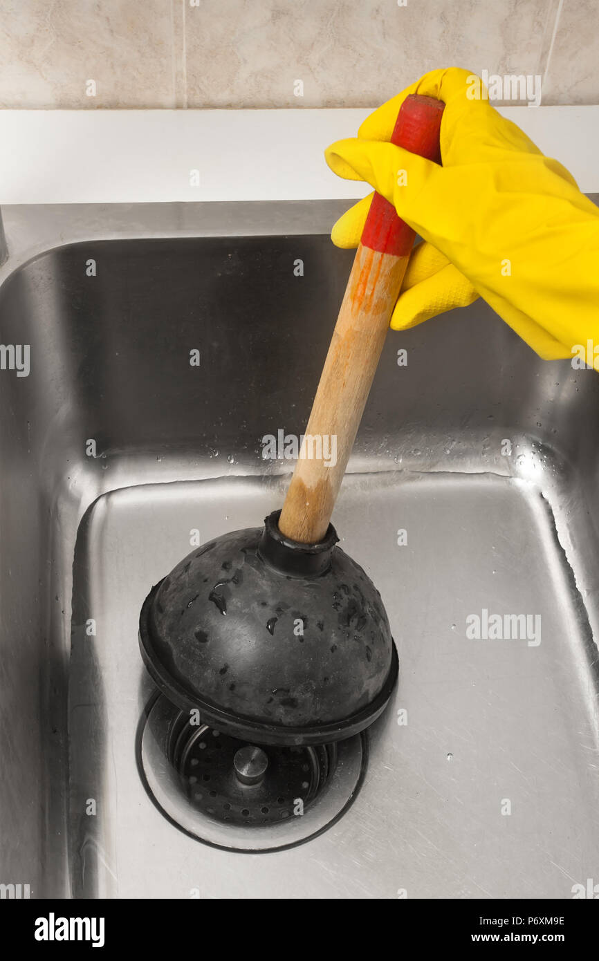 Hand in Hand mit einem Stößel zur Reinigung eine verstopfte Waschbecken Stockfoto