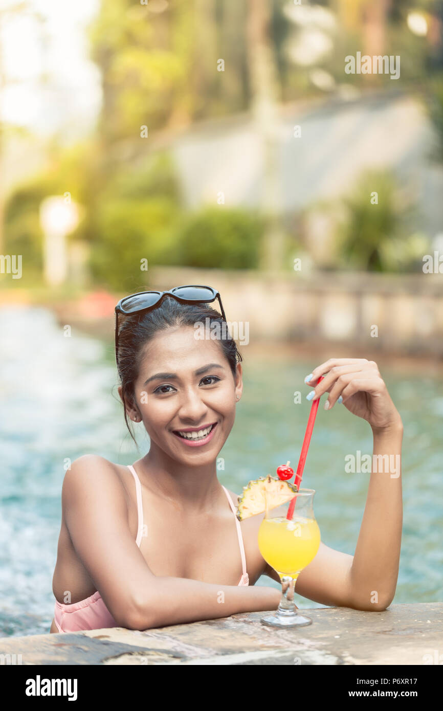 Porträt einer wunderschönen asiatischen Frau trinkt ein Ananas Cocktail im Pool Stockfoto