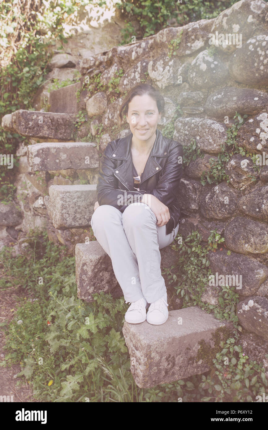 Lächelnde Frau sitzt auf einem Stein Treppe Stockfoto