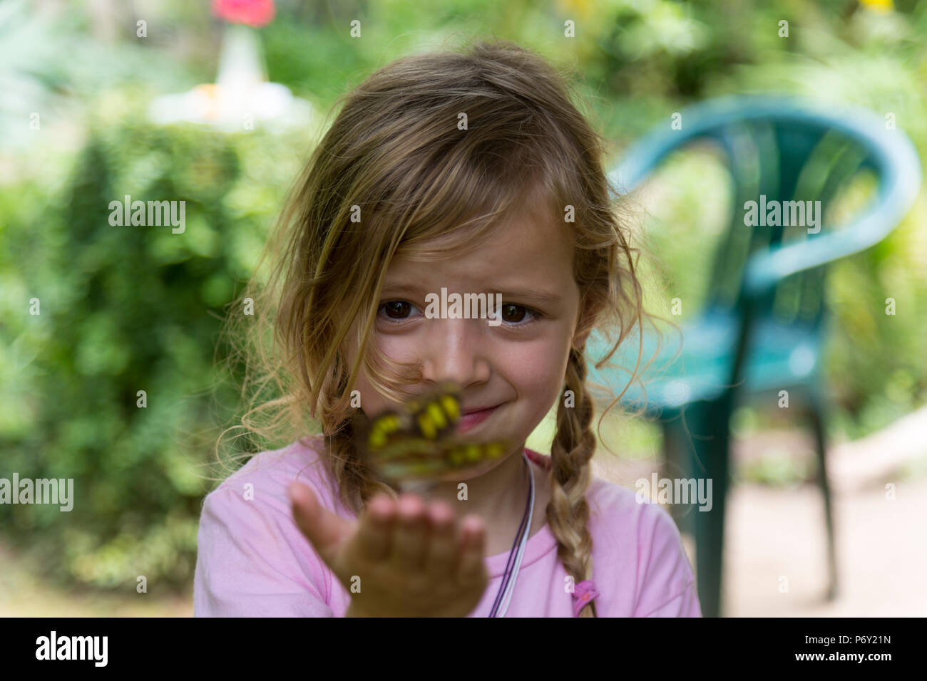 Grinsend blonde Mädchen mit einem gelben beschmutzt Schmetterling in der Hand. Selektive konzentrieren. Medium close up. Stockfoto