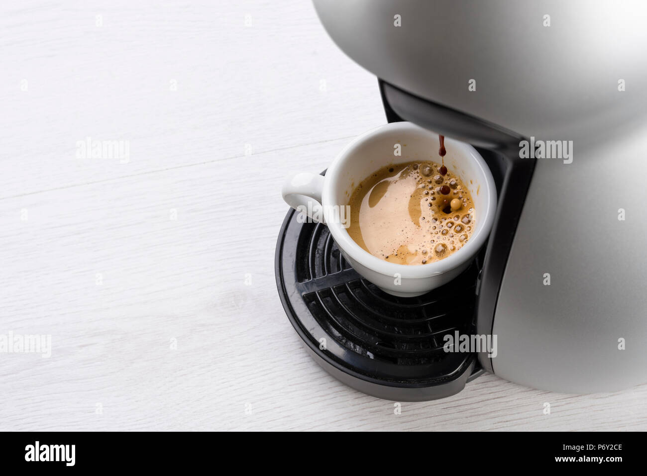 Kaffeemaschine füllt eine Tasse Kaffee auf Tisch Stockfoto