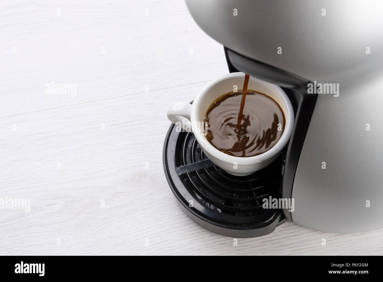 Kaffeemaschine füllt eine Tasse Kaffee auf Tisch Stockfoto