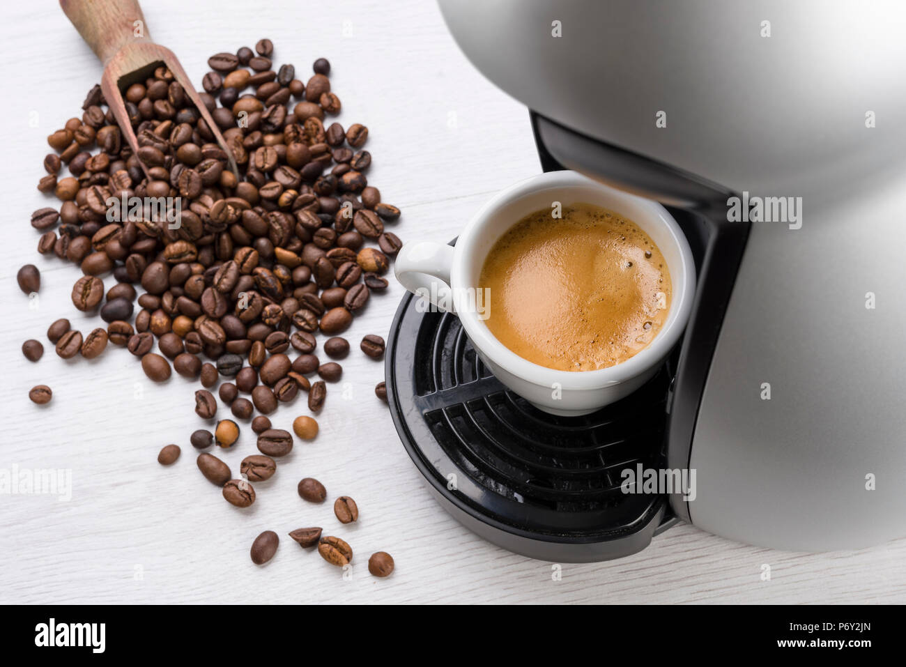 Tasse Kaffee nur gefüllt auf der Maschine mit Kaffeebohnen auf Tisch Stockfoto