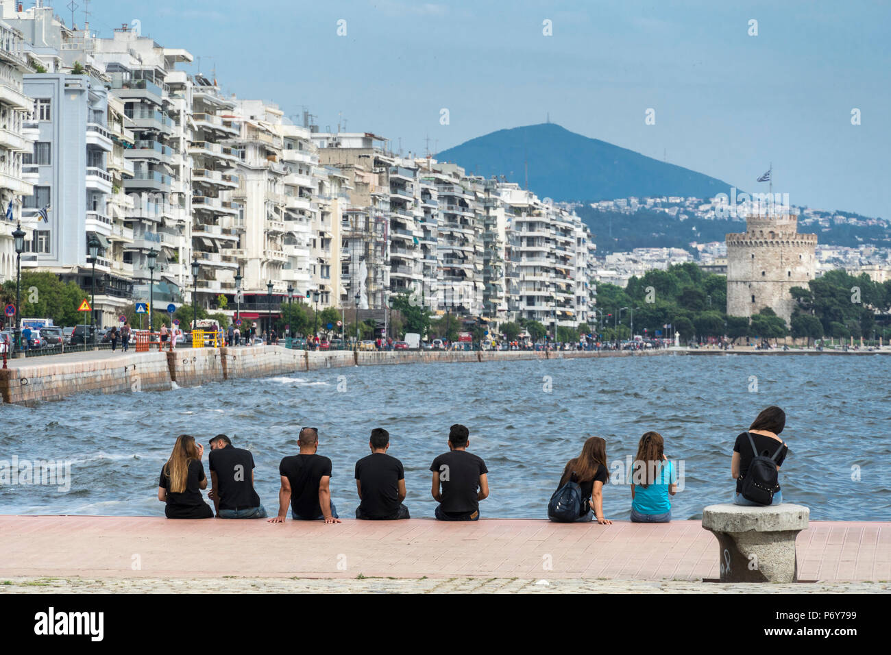 Menschen entspannend auf Thessaloniki Waterfront mit Apartment Blocks auf Nikis Avenue und den Weißen Turm im Hintergrund, Mazedonien, Nordgriechenland Stockfoto