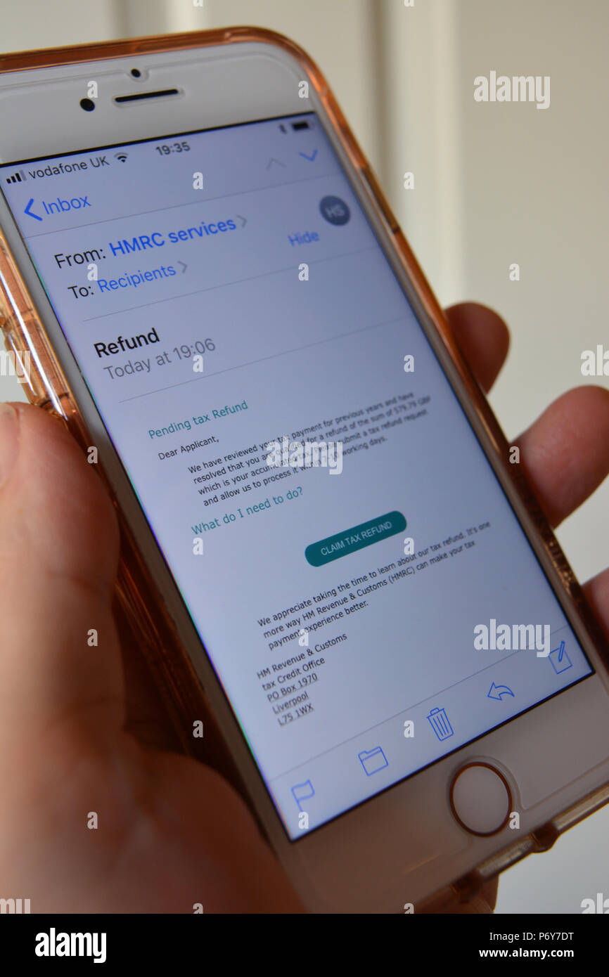 Handy in der Hand der Frau mit einem scam/Phishing-E-Mails, die angeblich von der HMRC, auf dem Bildschirm angezeigt werden Stockfoto