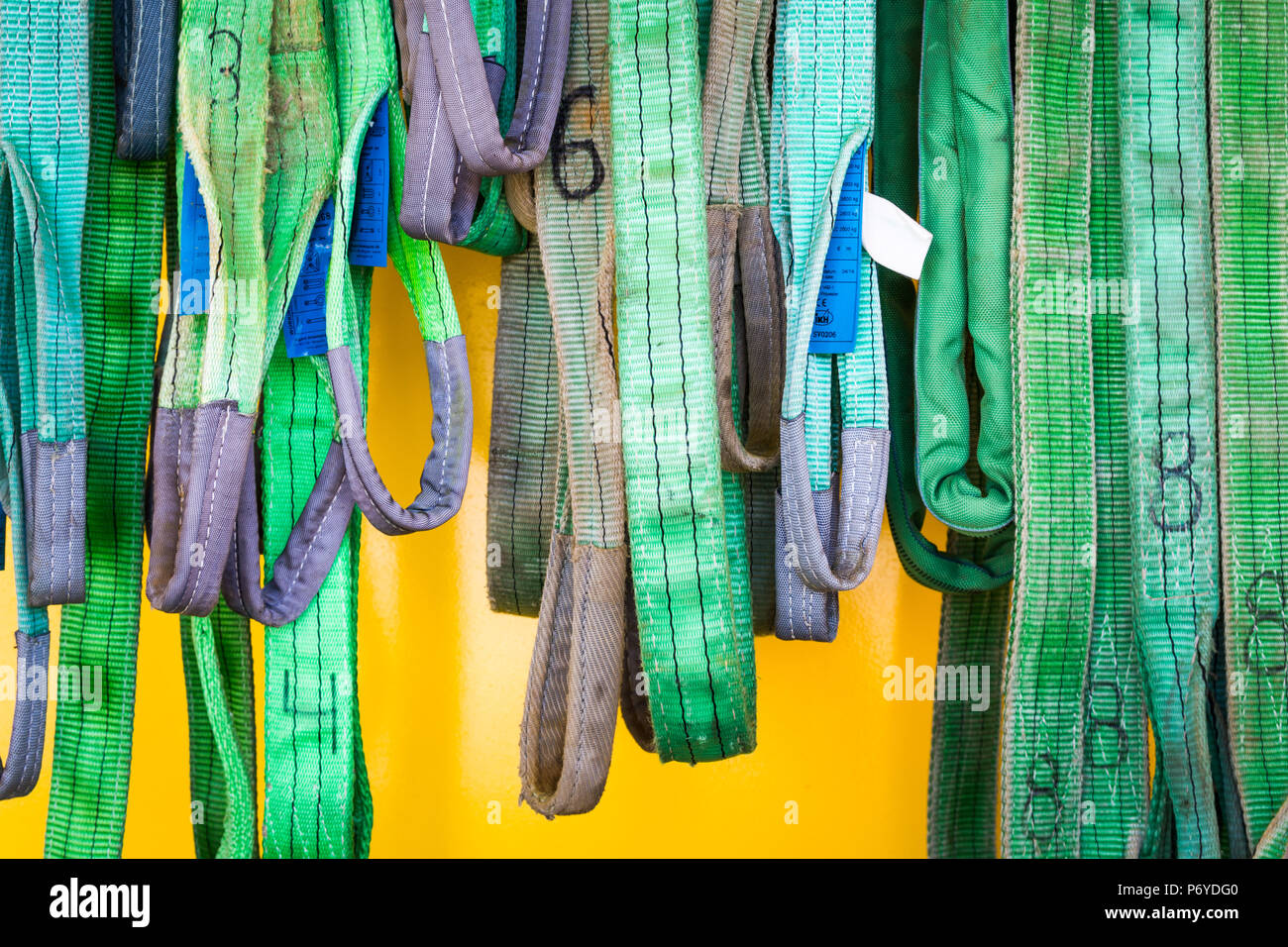 Abgenutzte nummeriert grün Seile hängen in verschiedenen Längen auf gelbem Hintergrund Stockfoto