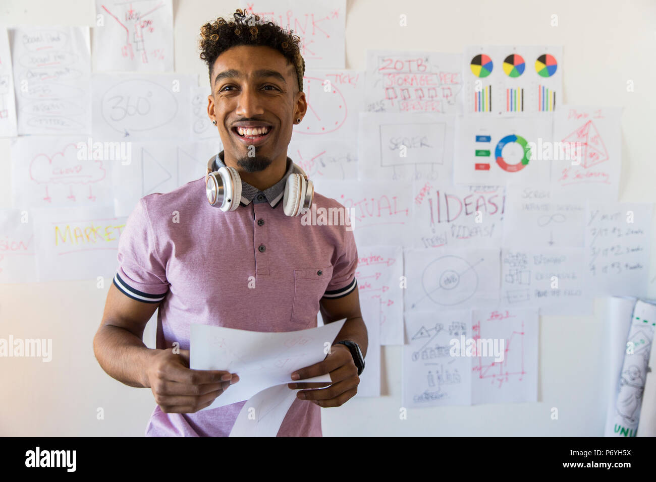 Porträt Lächeln, zuversichtlich, dass kreative Unternehmer hängenden Papierkram auf Office Wand Stockfoto