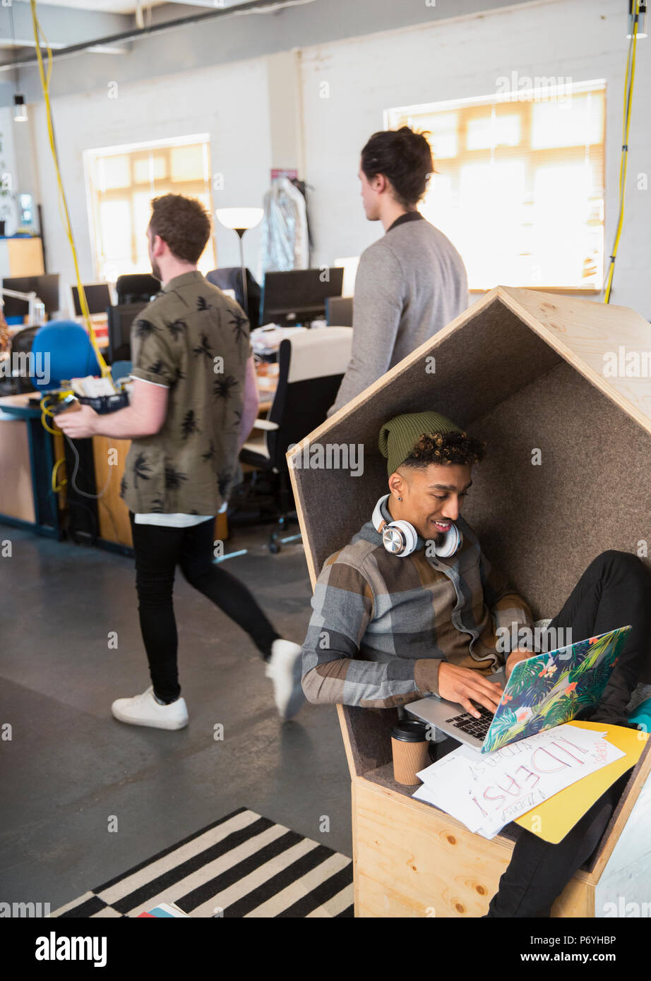 Kreative Geschäftsmann mit Kopfhörern mit Laptop im Büro Ablage Stockfoto