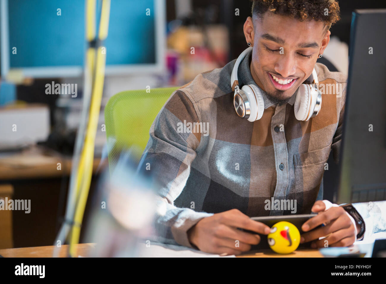 Kreative Geschäftsmann mit Kopfhörern texting mit Smart am Schreibtisch Stockfoto