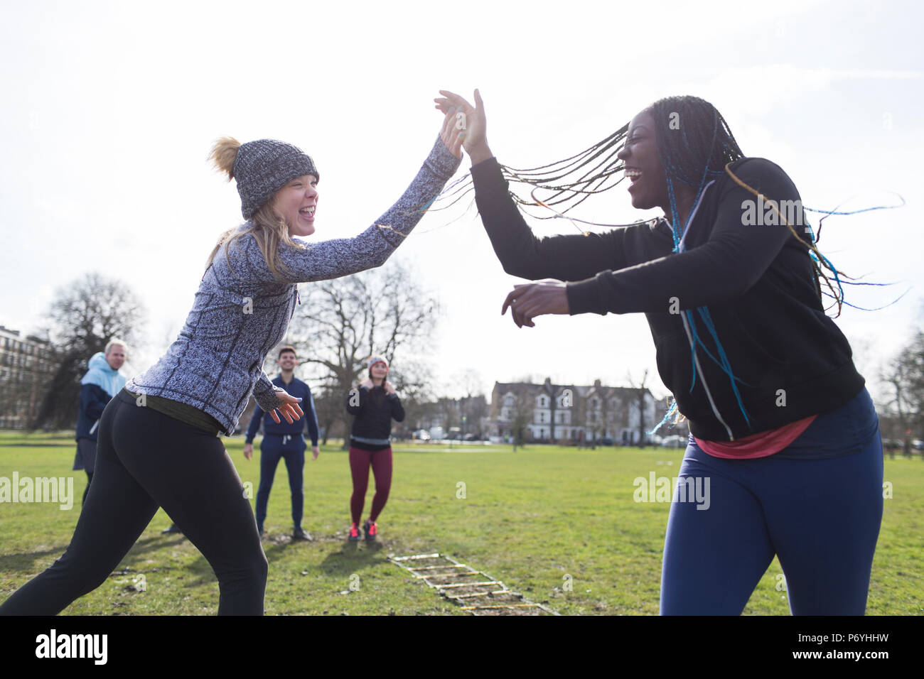 Begeisterte Frauen, high-Fiving, trainieren im sonnigen Park Stockfoto