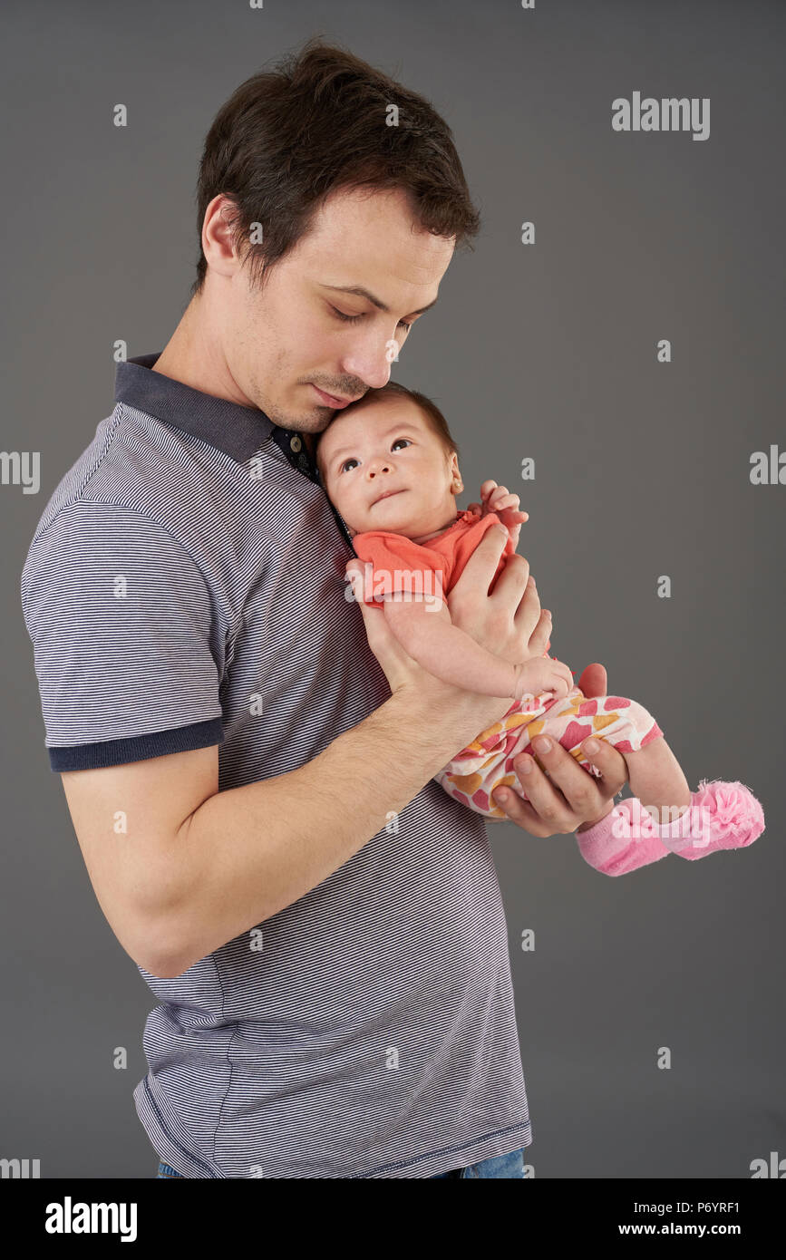 Junge Vater mit kleinen Baby auf grauem Hintergrund Stockfoto