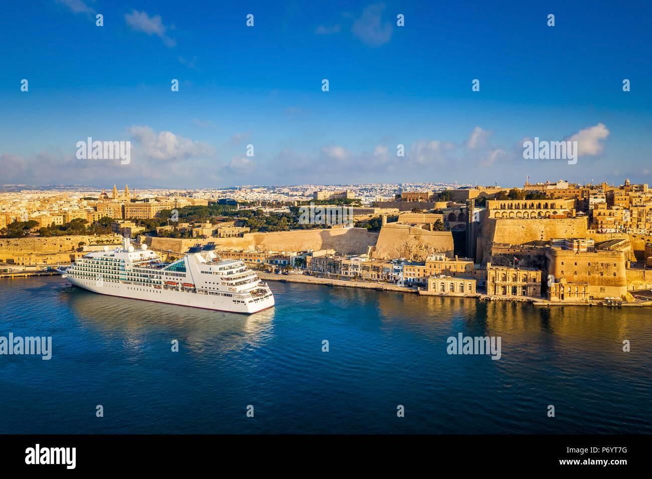 Valletta, Malta - Kreuzfahrtschiff in den Grand Harbour bei Sonnenaufgang mit der antiken Stadt Valletta im Hintergrund Stockfoto