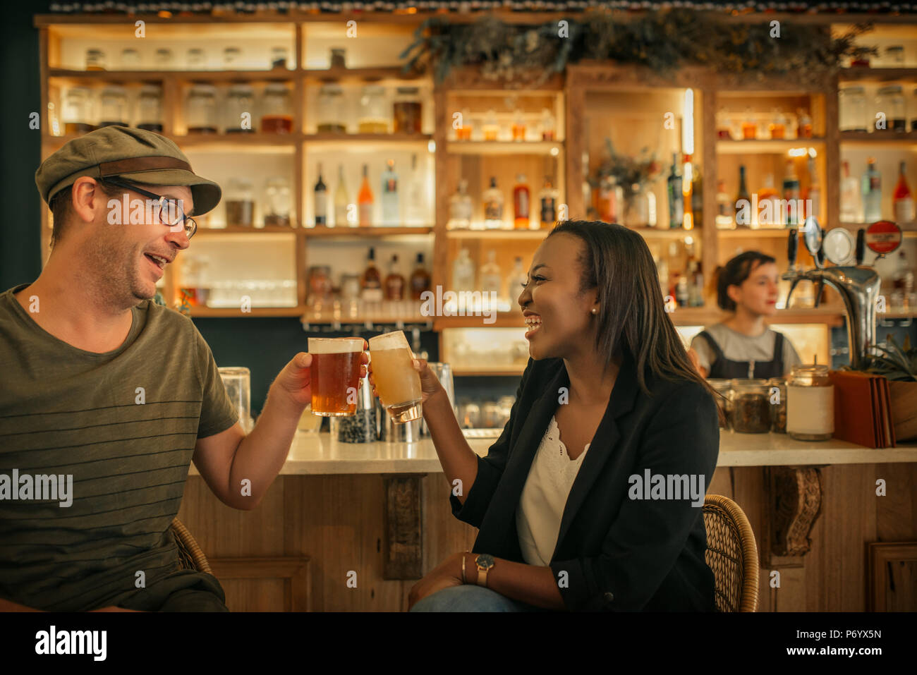 Zwei lächelnde junge Freunde jubeln mit Getränken in der Bar Stockfoto