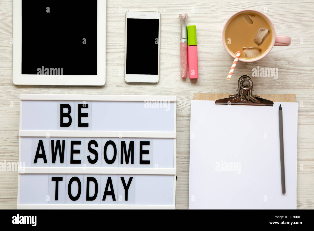 Feminine Arbeitsplatz mit Tablet, noticepad, Blatt, Latte Ice und "ehrfürchtig Sein heute' Wörter auf Lightbox über weiß Holz- Oberfläche, Ansicht von oben. Von oben. Stockfoto