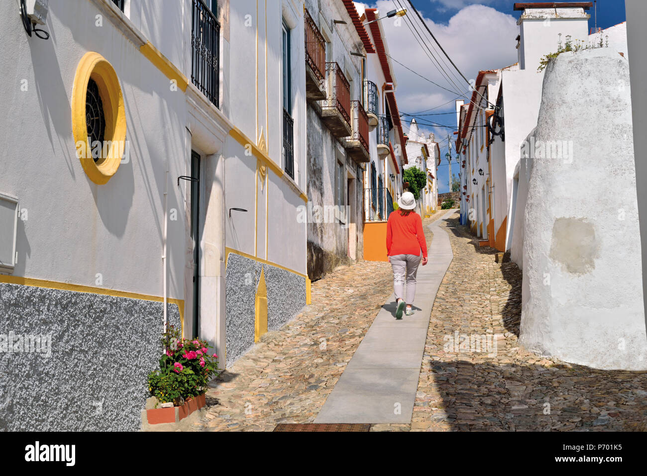 Frau mit roten Pullover zu Fuß entlang der kleinen gepflasterten Gasse dazwischen mittelalterlichen weiss getünchten Häusern Stockfoto