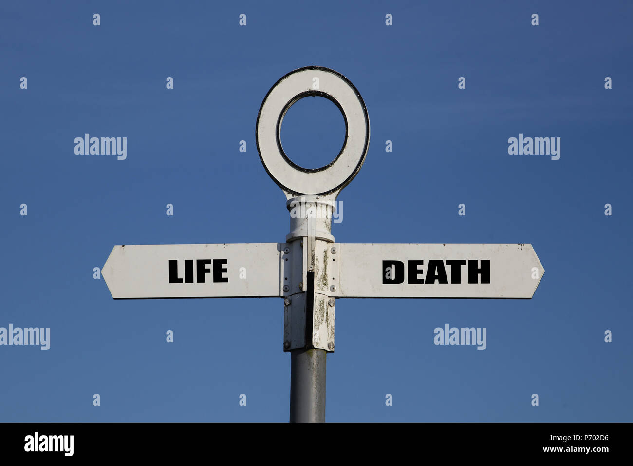 Alte Straße mit Leben und Tod zeigen in entgegengesetzte Richtungen vor blauem Himmel Stockfoto