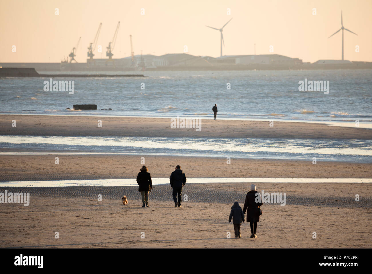 Die Spaziergänger am Strand bei Sonnenuntergang mit Docks von Boulogne-sur-Mer, Calais, Pas-de-Calais, Ile-de-France, Frankreich, Europa Stockfoto