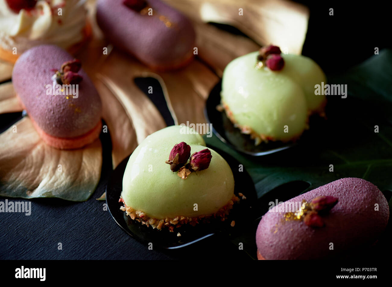 Moscovie Kuchen lila und Zitronengelb. Pistazien und Obst. Kulinarische Kunst Gold Leaf monstera Stockfoto