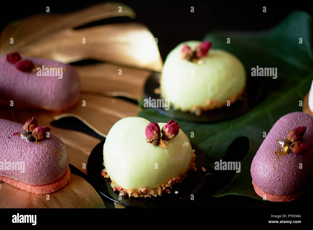 Moscovie Kuchen lila und Zitronengelb. Pistazien und Obst. Kulinarische Kunst Gold Leaf monstera Stockfoto