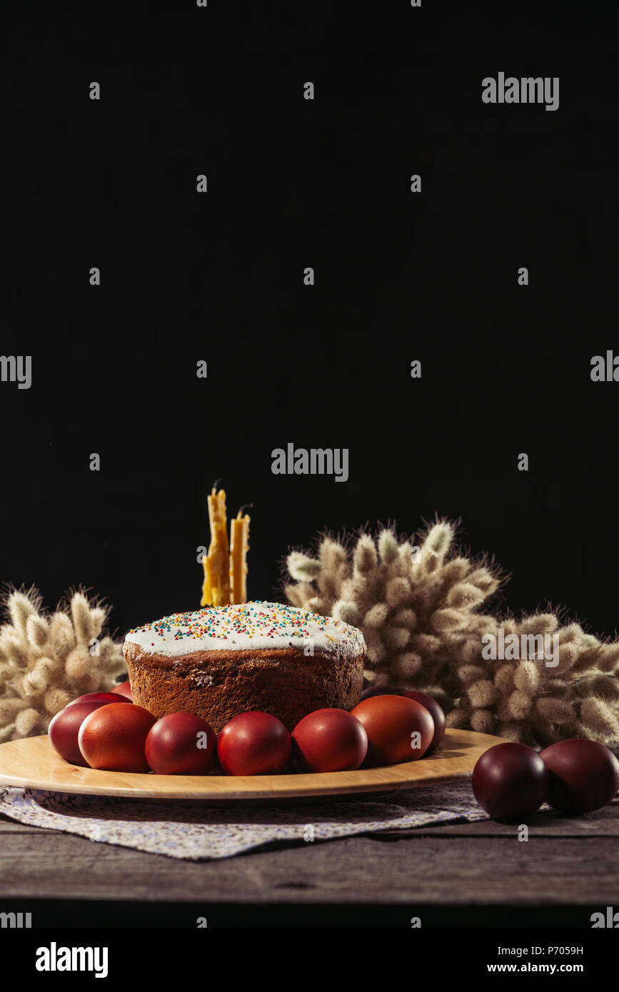 Bemalte Hühnereier, Ostern Kuchen und Kerzen auf hölzernen Tisch Stockfoto