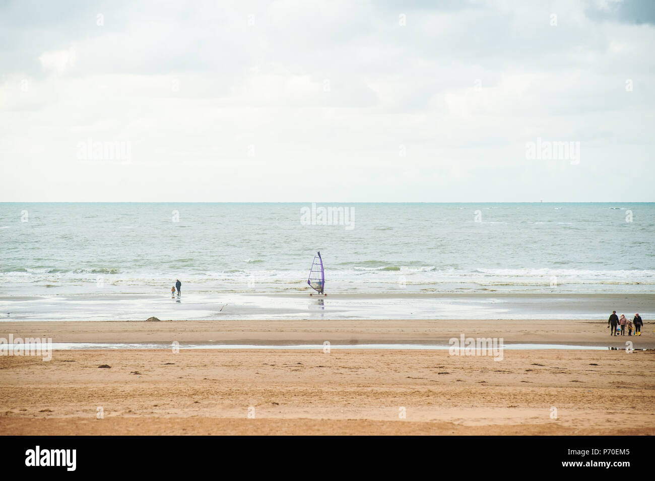 Surfen am Strand vor der Wellen im Herbst mit einigen Menschen zu Fuß durch Stockfoto