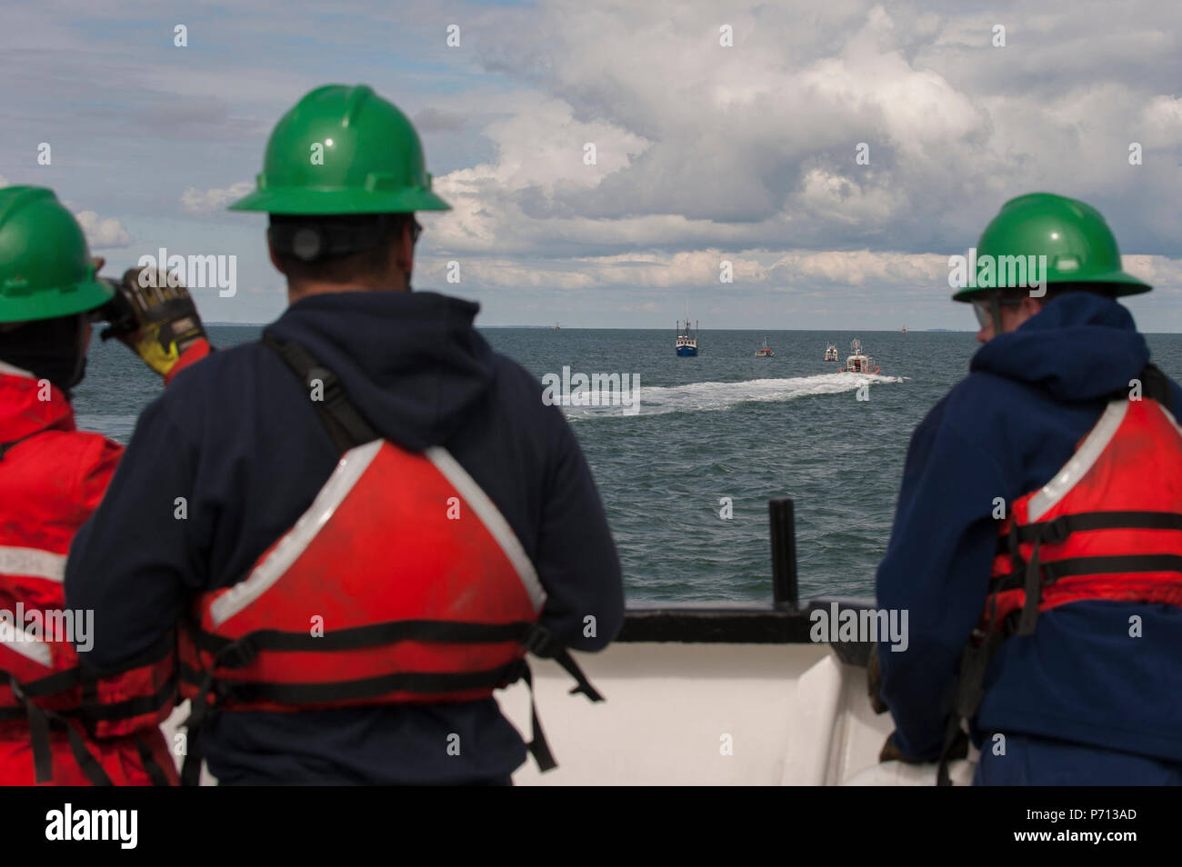 Besatzungsmitglieder der Coast Guard Cutter Eiche Watch vom Bug des Cutter als ihre kleine Crew unterstützt das Fischereifahrzeug Jupiter, die ein Feuer im Maschinenraum, Donnerstag, 11. Mai 2017, in der Nähe von Hyannis, Massachusetts berichtet. Zwei Mitglieder der kleinen Crew an Bord Jupiter und verwendet einen Feuerlöscher, den Schwelbrand. Stockfoto