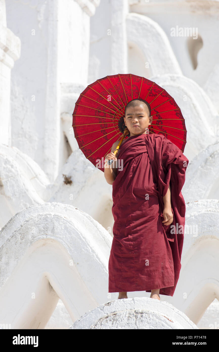 Junge Mönch in rot gekleidet, mit roten Sonnenschirm am Myatheindan Pagode (weiße Tempel) in Mingun, Myanmar (Burma), Asien Stockfoto