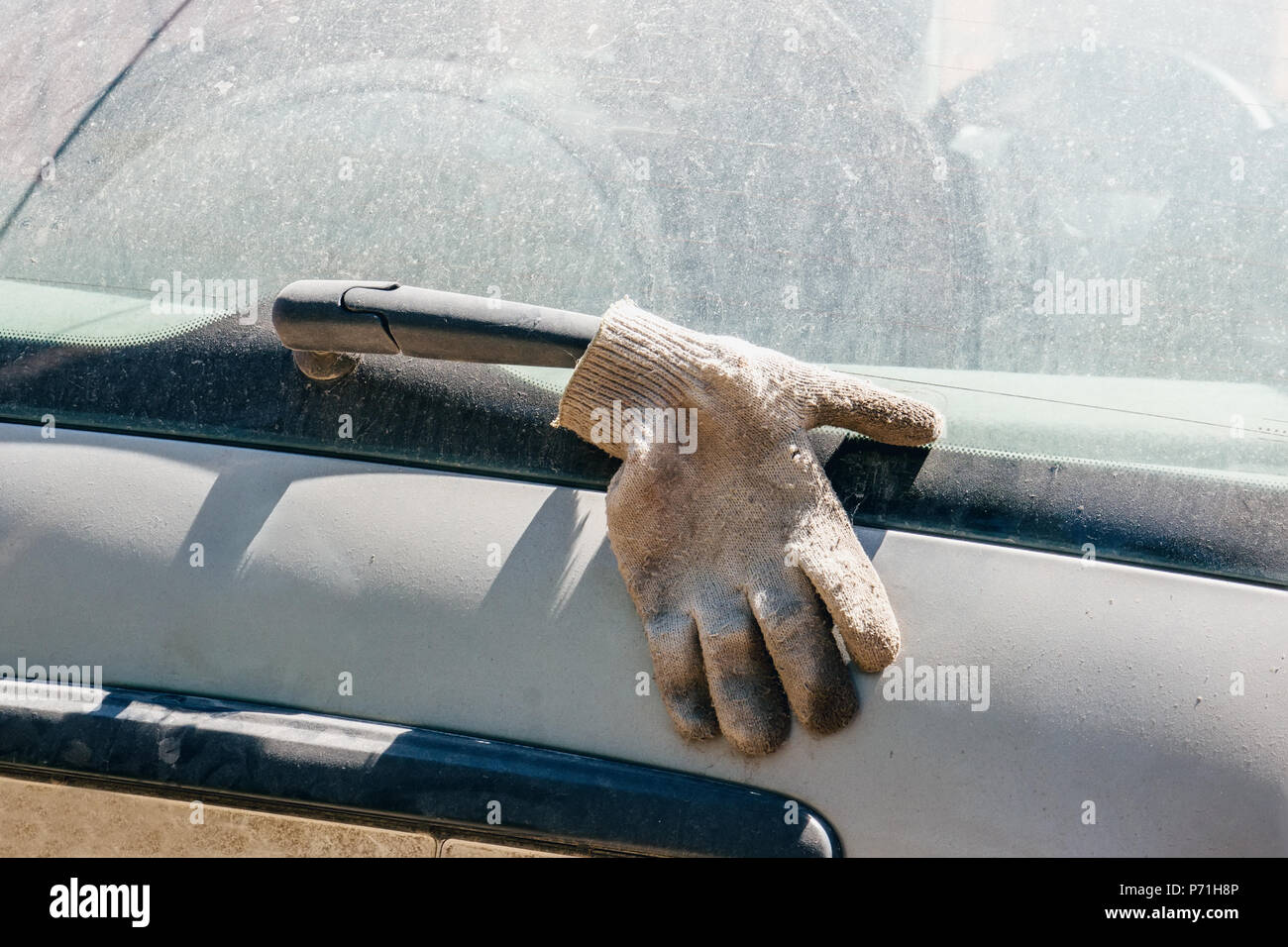 Der Handschuh auf dem Wischerblatt. Reinigung verschmutzte Glas auf dem Auto. Stockfoto