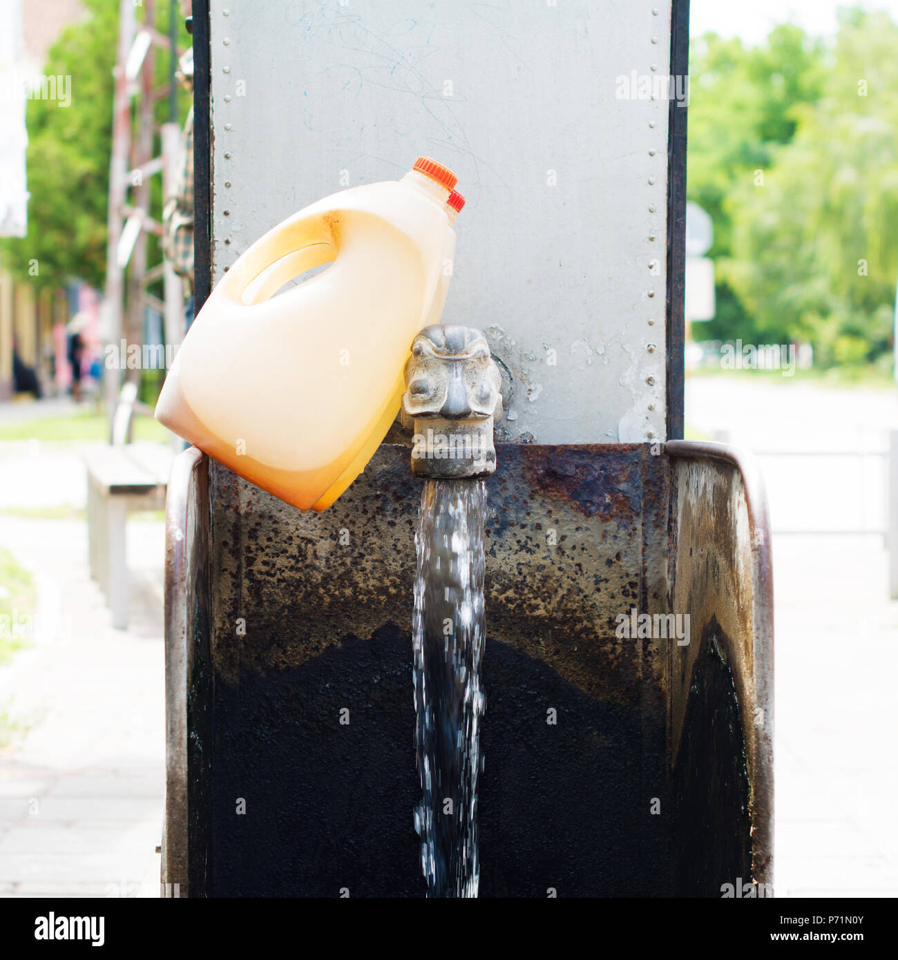 Wasser Brunnen auf einem fließenden artesischen Brunnen installiert, für die öffentliche Nutzung. Zwei Kunststoff korbflaschen am Zapfen lehnte. Stockfoto