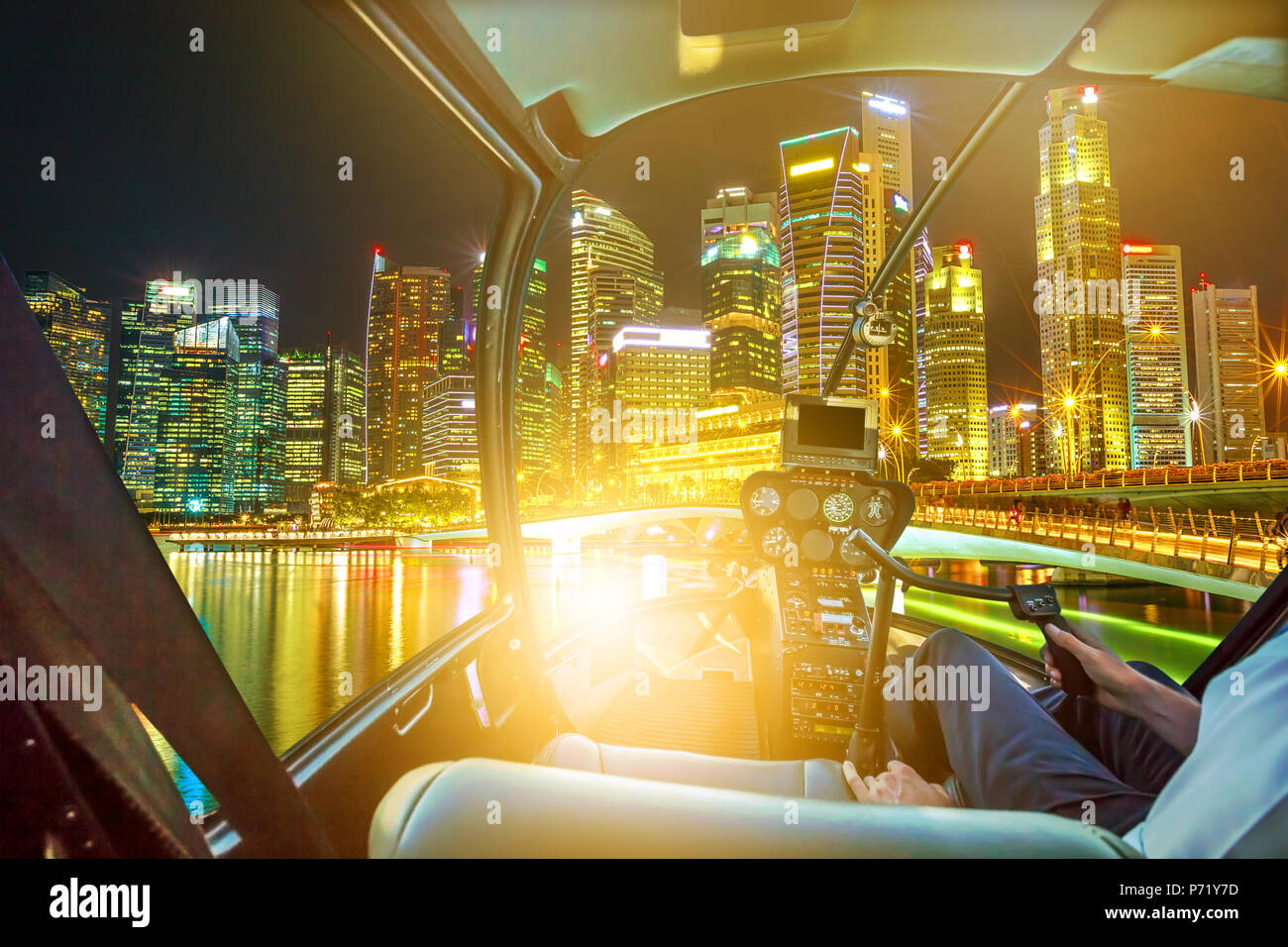 Helicopter Cockpit auf Singapore Downtown Skyline mit Wolkenkratzern der Geschäftsviertel und Brücke in der Marina Bay Promenade. Rundflug über Singapur mit die Lichter der Nacht reflektiert in der Bucht. Stockfoto
