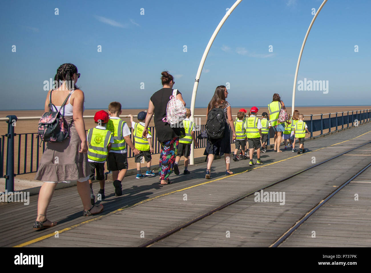 Kinder mit Hi-vix-Tabards für einen Spaziergang am Southport Pier, Merseyside, 4. Juli 2018. Wetter in Großbritannien. Blauer Himmel und strahlende Sonne im Nordwesten als Touristen, Schulkinder und Besucher machen einen Spaziergang auf dem Seebrücke. Credit:MediaWorldImages/AlamyLiveNews Stockfoto