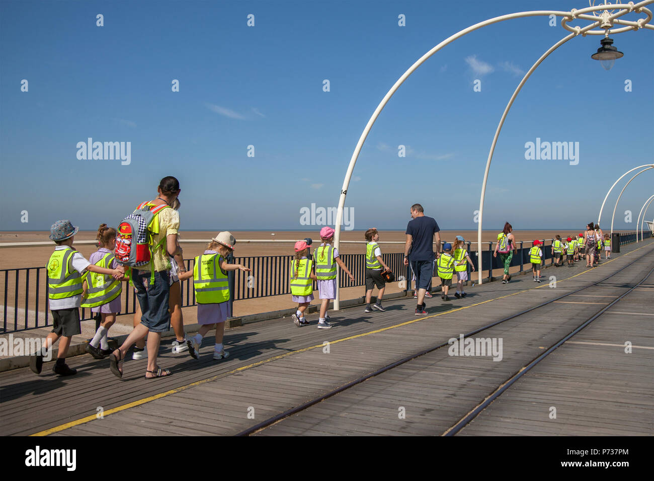 Kinder mit Hi-vix-Tabards für einen Spaziergang am Southport Pier, Merseyside, 4. Juli 2018. Wetter in Großbritannien. Blauer Himmel und strahlende Sonne im Nordwesten als Touristen, Schulkinder und Besucher machen einen Spaziergang auf dem Seebrücke. Credit:MediaWorldImages/AlamyLiveNews Stockfoto