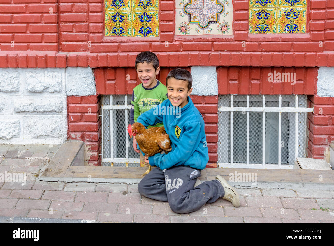 Nicht identifizierte Kinder halten und betrachten Sie ein braunes Huhn an der Straße in Istanbul, Türkei, 09. April 2017 Stockfoto