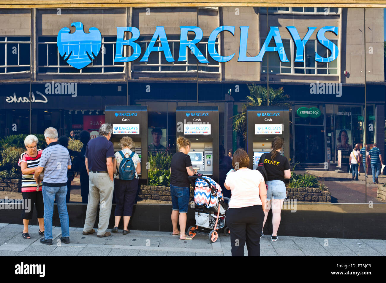 Kunden Warteschlange außerhalb der Barclays Bank Geldautomaten in Plymouth, Devon, England Großbritannien Stockfoto