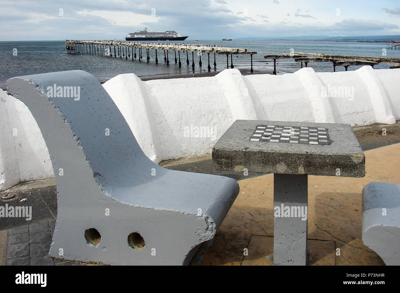 Kreuzfahrtschiff im Ozean mit Stein Stein Stühle und Schachbrett im Vordergrund in Punta Arenas, Chile Stockfoto